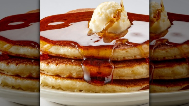 A stack of pancakes with syrup and butter from Village Inn.