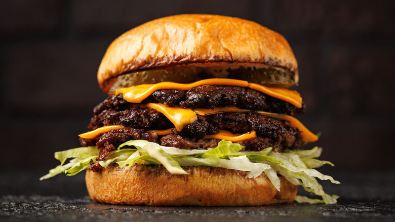 triple smashburger with cheese and lettuce sitting on a black counter