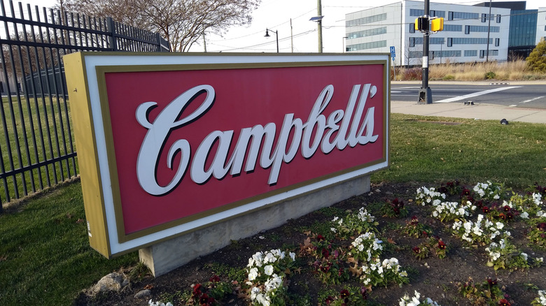Sign outside Campbell's building with brand's logo in front of flowers
