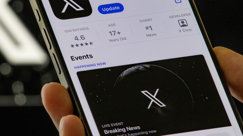 Close up of hand holding smartphone on a page to download the X app