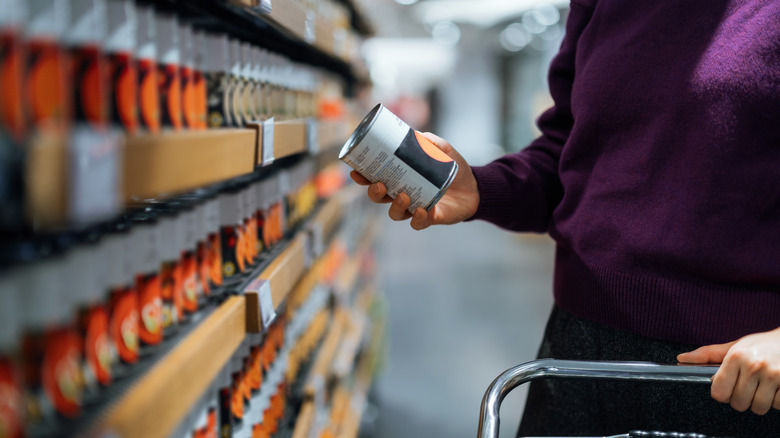 Shopper looking at can of food in grocery store