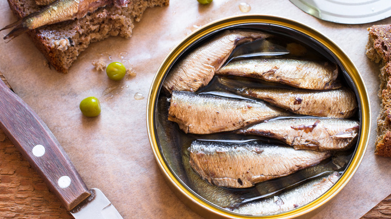 Open tin of sardines with bread and knife