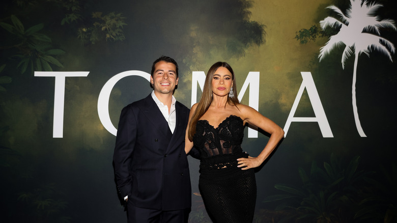 Sofia Vergara and her son Manolo posing together in front of an advertisement for TOMA