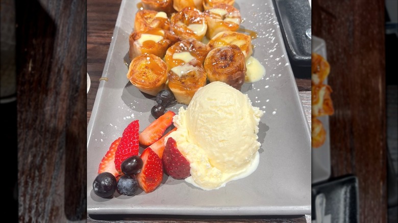 Small, fried pieces of banana arranged on a long tray with ice cream.