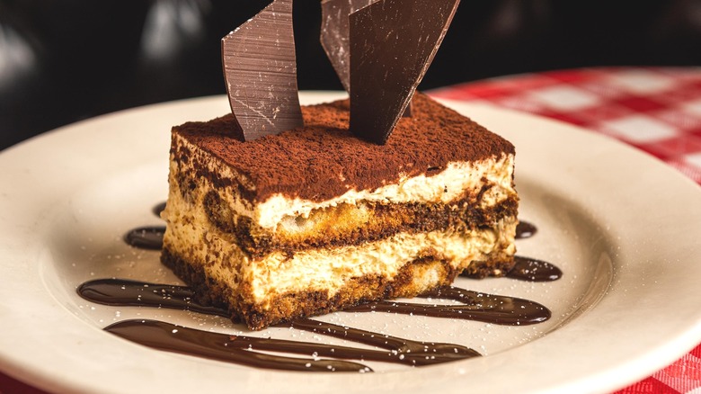 A chocolate-topped tiramisu on a white plate.