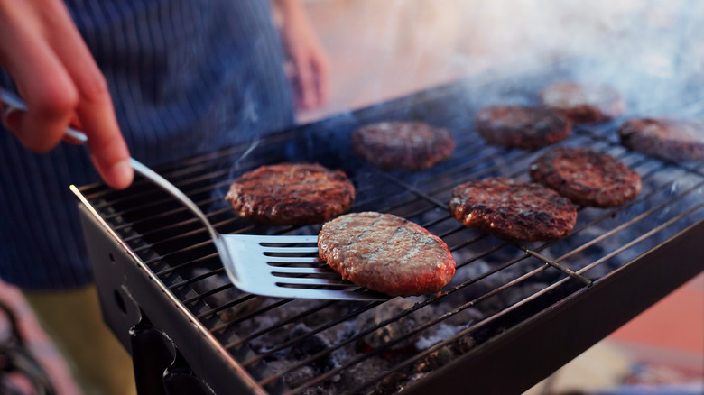 Close up of person flipping burger patties on the grill
