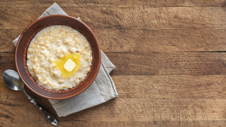 a pat of butter in oatmeal in brown bowl