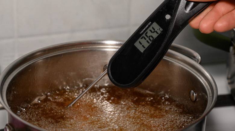 person testing oil with digital thermometer