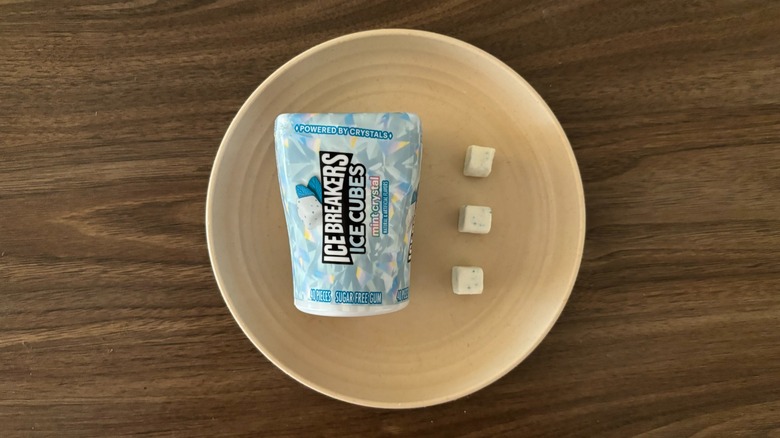 Ice Breakers Mint Crystal Ice Cubes Sugar-Free Chewing Gum packaging and pieces of gum on round beige plate
