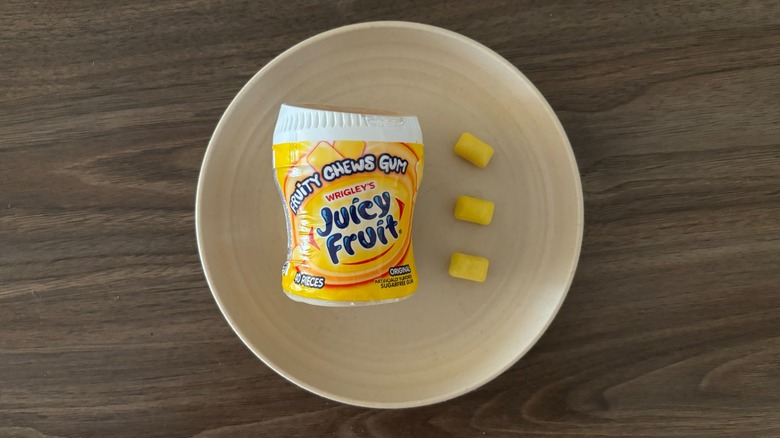 Juicy Fruit Original Bubble Gum in a bottle and pieces of gum on round beige plate
