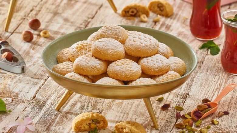 a plate of egyptian kahk cookies with powdered sugar on a wooden table