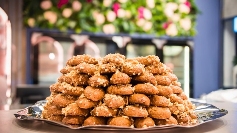 a mound of melomakarona, greek honey cookies, on a silver platter in front of a mantle