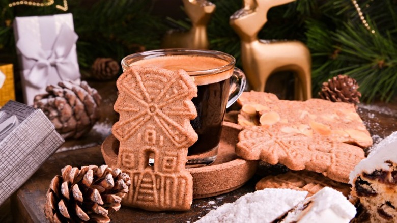 windmill shaped speculaas cookies next to a cup of coffee and various christmas decorations