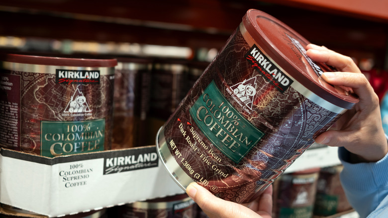 Customer holding tub of Kirkland signature coffee near display