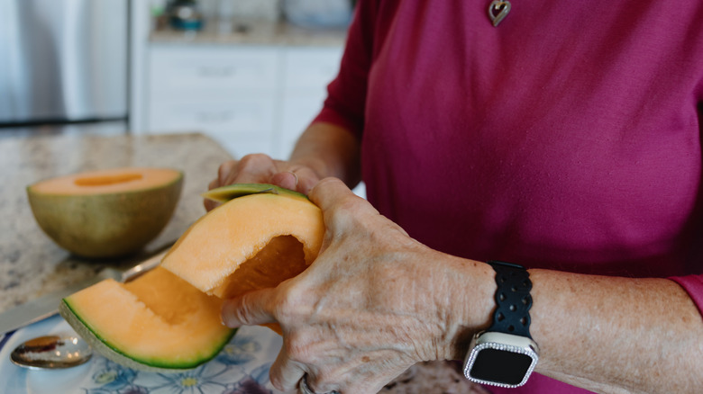 person cutting a cantaloupe