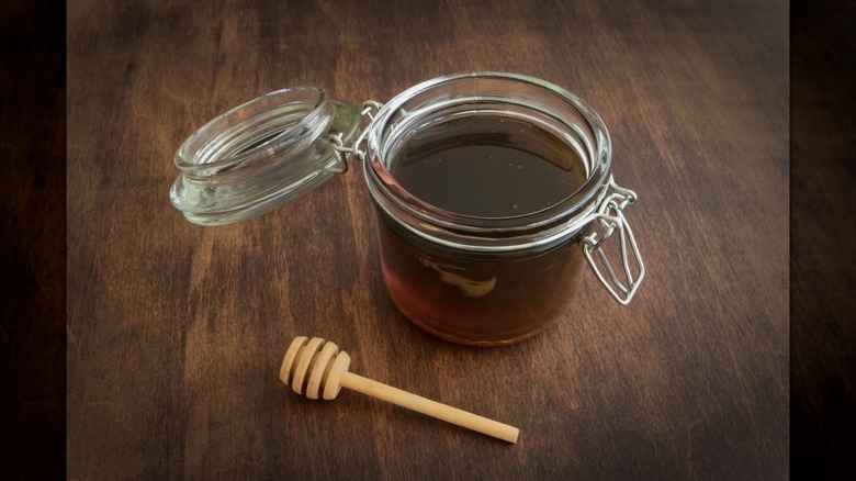 A jar of sorghum syrup on wooden surface