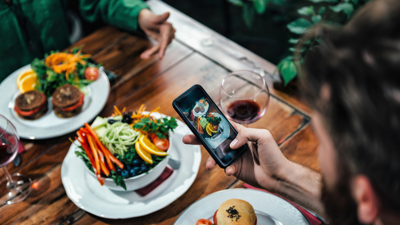 Diner taking photo of meal at restaurant