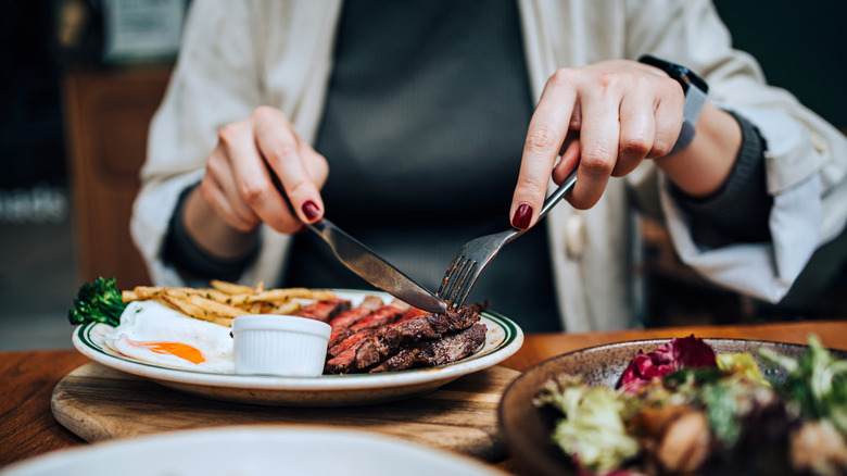 Woman cutting steak in restaurant
