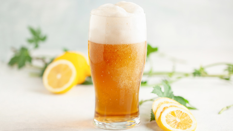 Shandy cocktail styled with lemon slices on a white background