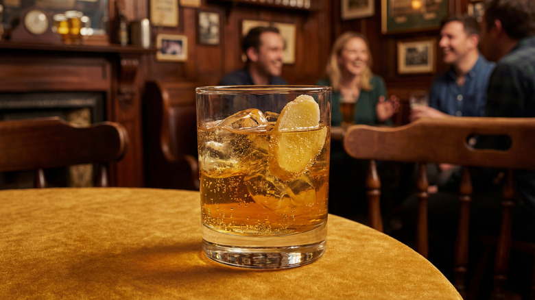A glass of whiskey and ginger ale on a table.
