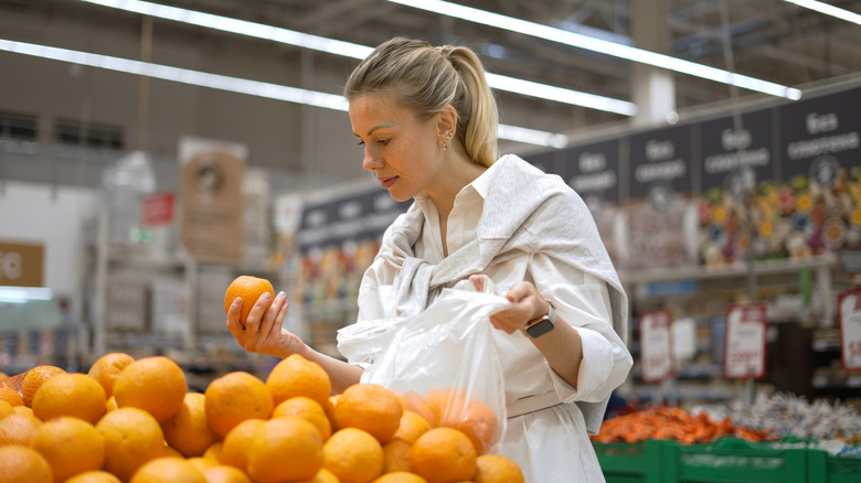 Woman inspecting orange from produce aisle