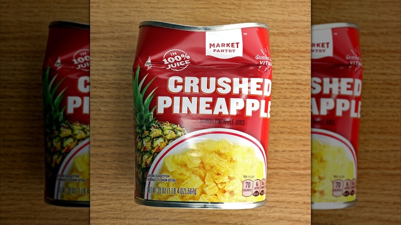 Dented red can of pineapple with Market Pantry branding