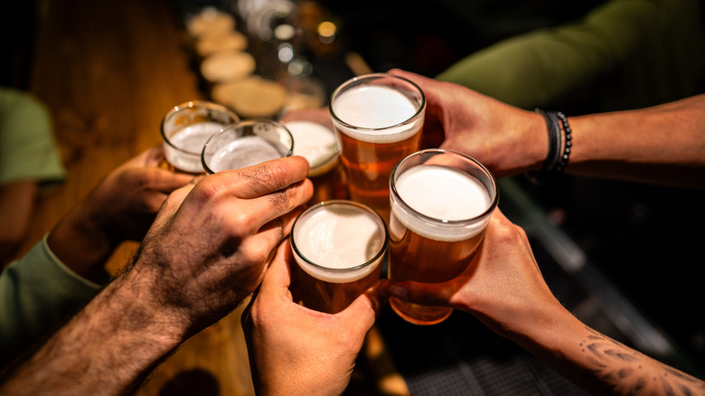 a group of people clinking beer glasses together