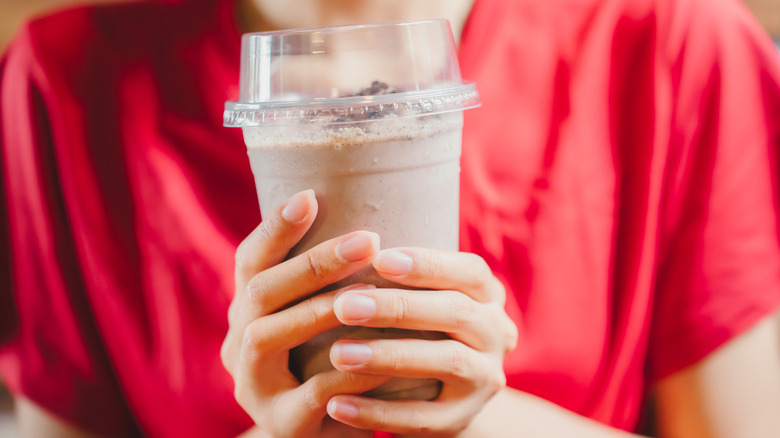 woman holding chocolate milkshake