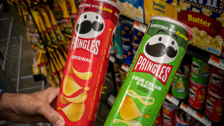 people holding up two pringles canisters
