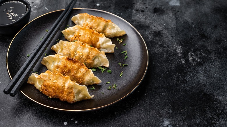 Asian Fried Dumplings, Jiaozi, Gyoza, Dim sum with meat and vegetables on plate. black background. top view.