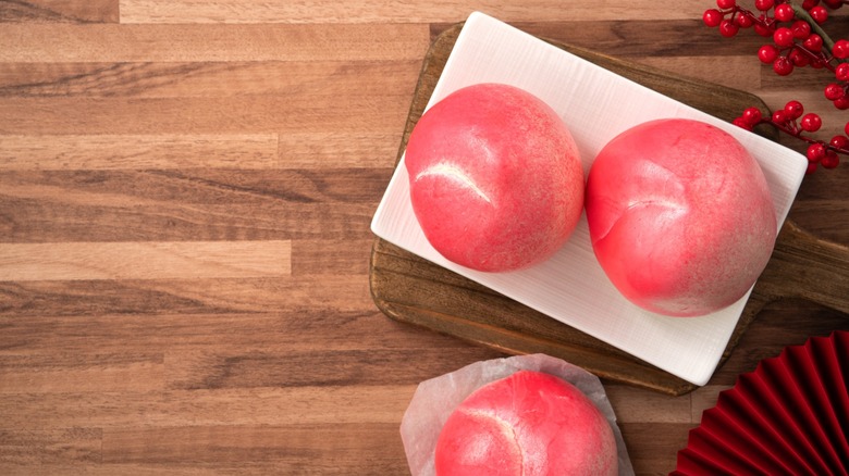 Pink Chinese peach birthday bun food longevity peach shoutao on wooden table background.