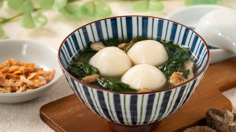 A striped bowl of tangyuan on a cutting board