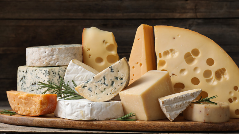 Piles of different cheeses on wooden cutting board