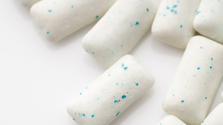 Pieces of white chewing gum flecked with blue against a white background