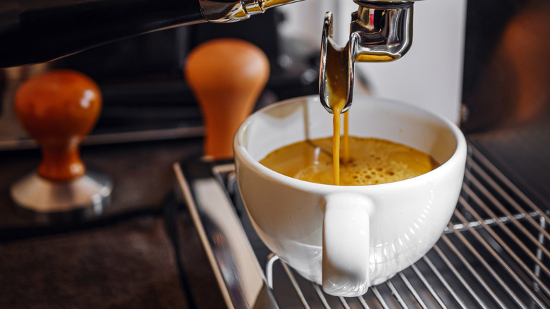 Espresso machine pouring coffee into white cup