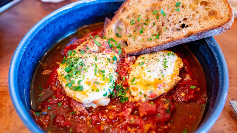 Shakshuka in a blue bowl with bread