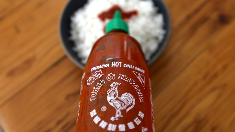 squirting sriracha on a bowl of rice