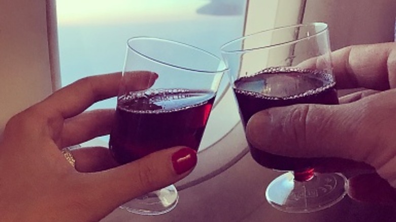 hands holding wine glasses on an airplane