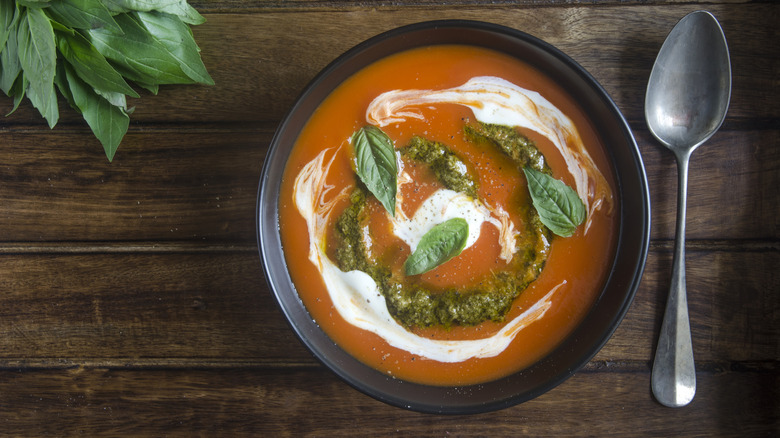Bowl of tomato soup with pesto, cream, and spoon