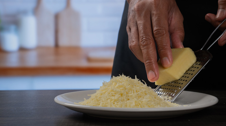 Hands grating parmesan onto plate