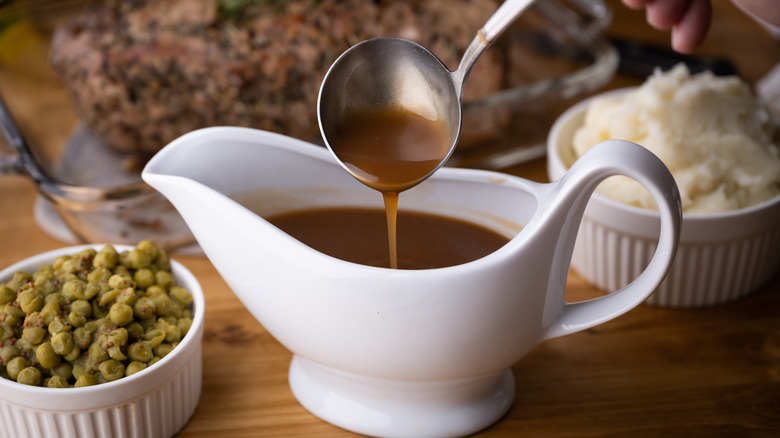 Ladle pouring brown gravy into gravy boat