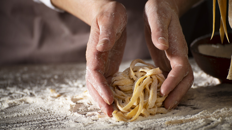 Hands cupping raw pasta