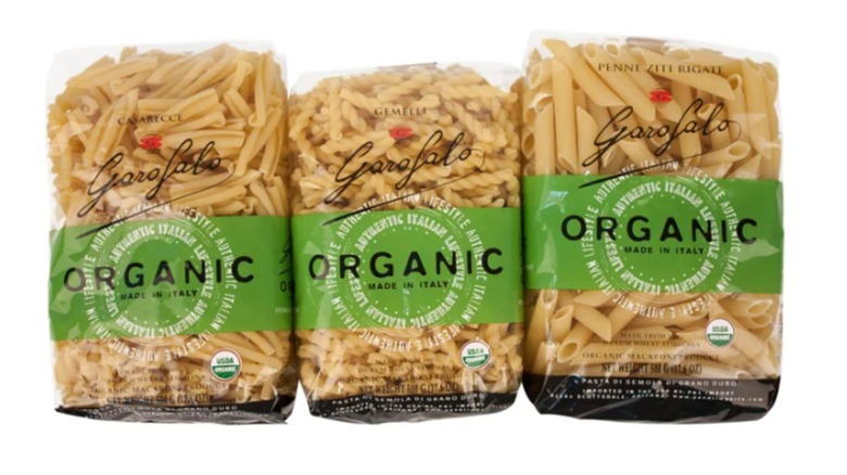 Three bags of uniquely shaped organic pasta on white background