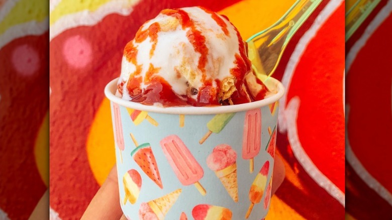 ice cream with red sauce in a light blue cup with an ice cream cone design