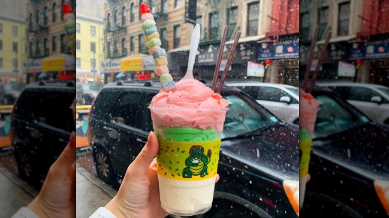 Plastic cup with pink, green, and cream-colored ice cream scoops with mochi skewer and pocky sticks from Chinatown Ice Cream Factory