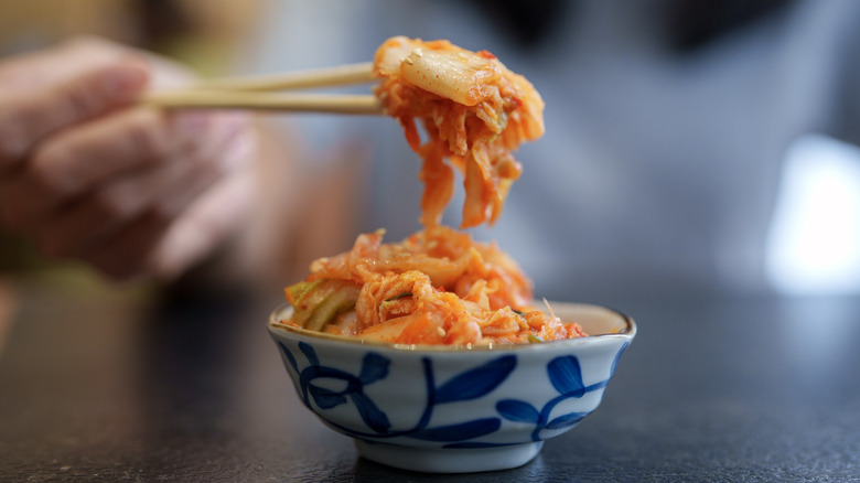 Chopsticks lifting kimchi from bowl