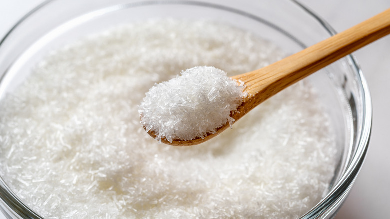 Wooden spoon lifting MSG from bowl