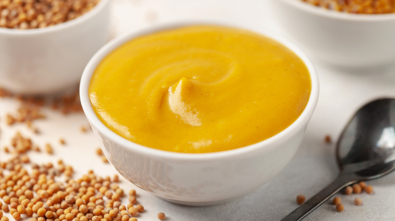 White dish of mustard with spoon