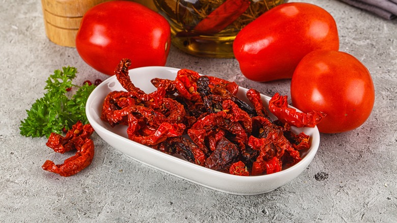 Sundried tomatoes in bowl with fresh tomatoes in background