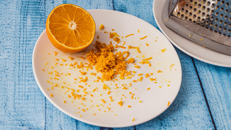 Orange and orange zest on plate with grater